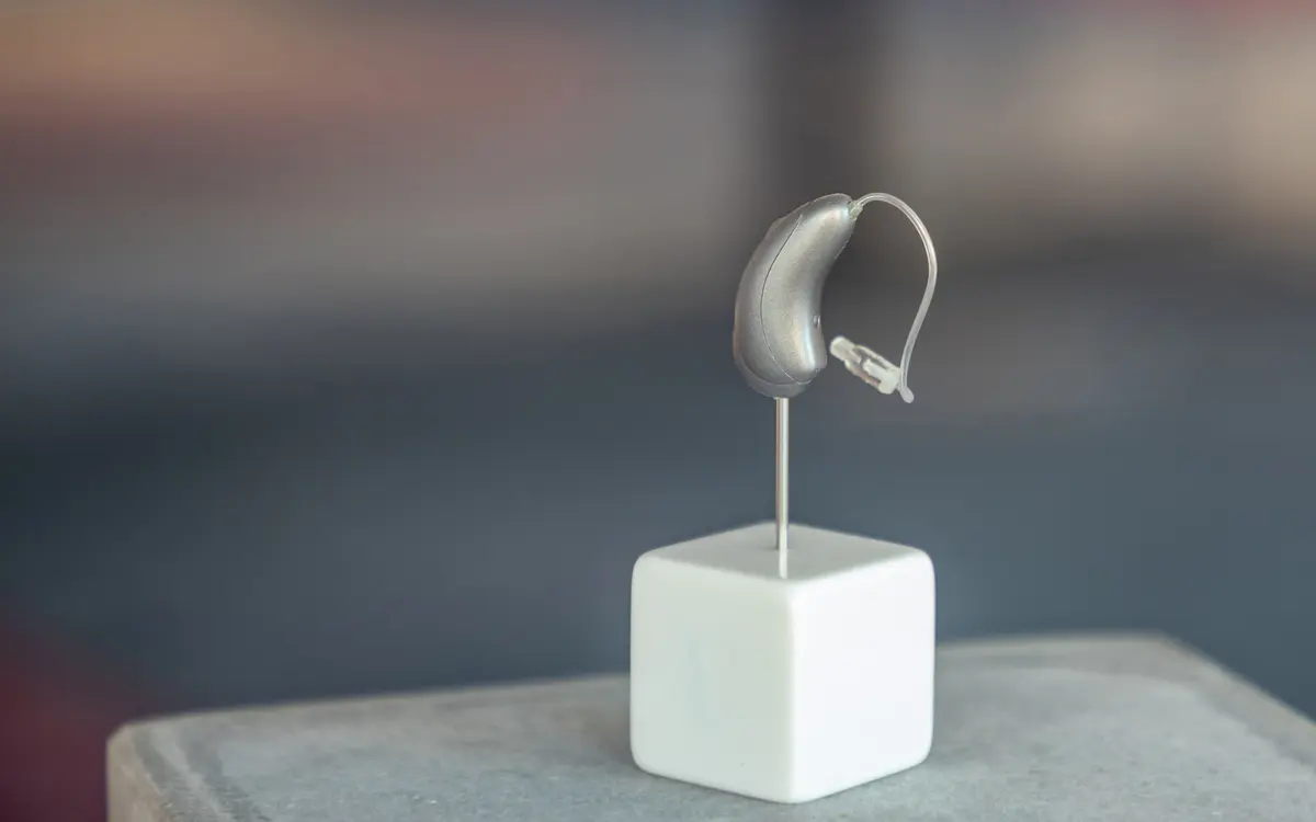 Aparelho auditivo retroauricular exposto em um suporte branco