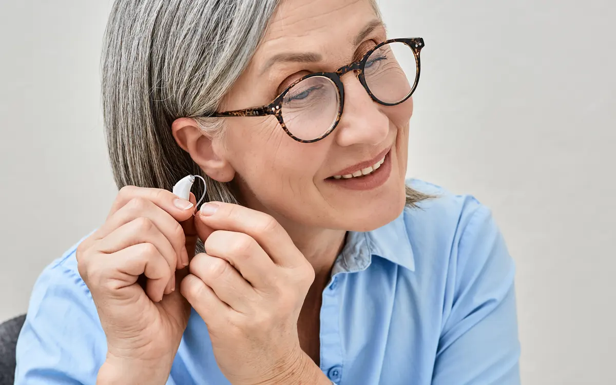 Senhora segurando um aparelho auditivo intra-auricular